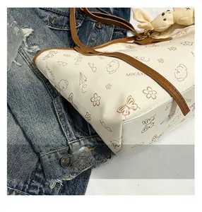 Close-up of printed cream tote bag featuring cute illustrations and a bunny charm