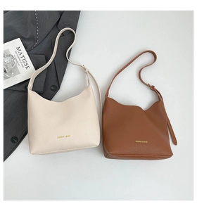 Detail view of cream and caramel hobo bags featuring pebble leather and gold lettering