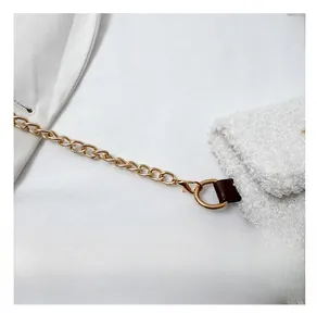 Detail of soft white plush fabric with premium gold chain strap and leather accents