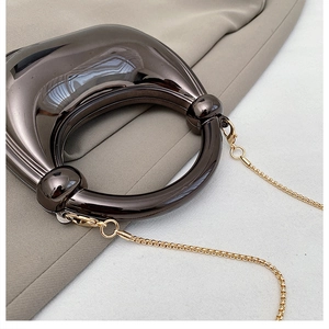 Detail of glossy metallic evening bag in gunmetal grey with gold chain strap