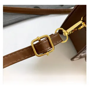 Detail of adjustable dark brown leather strap with polished gold-tone metal hardware buckle
