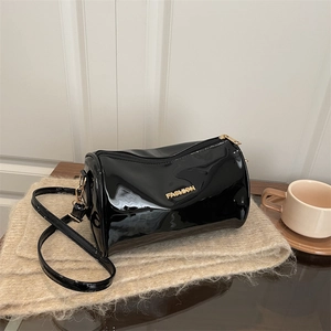 Minimalist black glossy leather cylinder bag with gold fashion label and shoulder strap