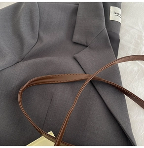 Detail of dark gray tailored blazer with interior label and brown leather strap