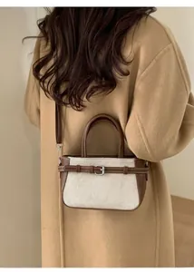 Vue détaillée du sac seau en toile et cuir marron porté avec un manteau beige élégant