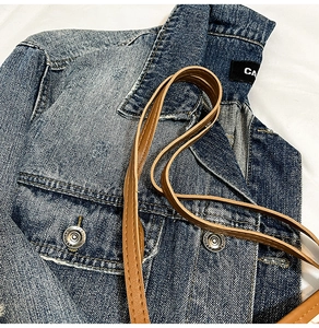 Detail shot of vintage blue denim fabric with silver metal buttons and brown leather strap
