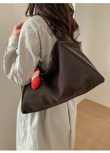 Dettaglio di una grande borsa tote in pelle marrone scuro con charm a nuvola rossa di peluche