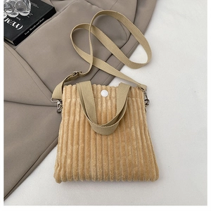 Detail of beige corduroy mini bag showing soft texture and button closure on white fabric