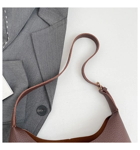 Close-up of deep brown litchi pattern leather shoulder bag with golden buckle details