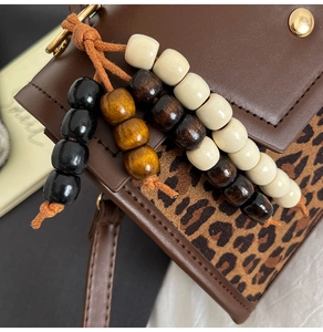 Détail de coutures léopard et breloques en perles de bois sur sac à main en cuir