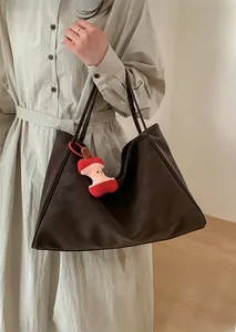 Dettaglio della borsa tote marrone scuro con ciondolo a forma di mela e grande capienza