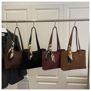 Détails de quatre sacs cabas à motif léopard avec foulards en soie suspendus sur un portant