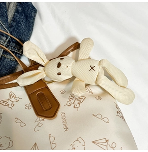 Close-up of a cute white bunny plush charm with embroidery on a canvas tote bag