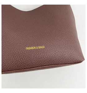 Detail view of the soft lychee grain leather texture and gold embossed lettering on the tote bag