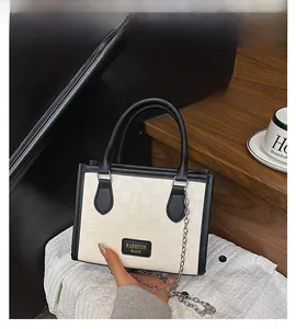 Close-up of checkered texture tote bag with black trim and elegant metal chain strap