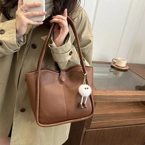 Brown leather tote bag with a cute white plush charm for daily commuting style