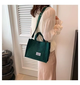 Green corduroy tote bag shown on model highlighting the versatile shoulder strap design