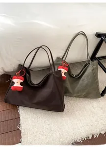 Dettagli di borse tote in pelle marrone e verde oliva con ciondoli in peluche a torsolo