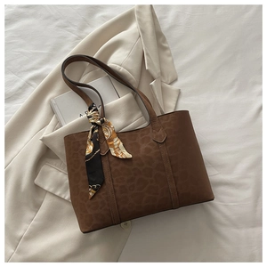 Détail d'un sac cabas léopard marron foncé avec foulard décoratif sur une veste chic