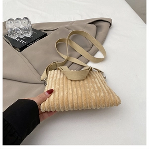 Detailed texture of beige corduroy crossbody bag with silver metal buckles and strap