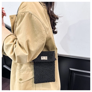 Detail of black faux fur mini crossbody bag with gold chain strap and metal lock closure
