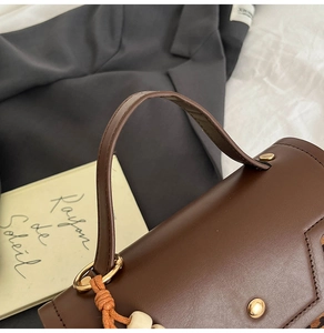 Detail of brown leather handbag featuring a golden ring handle and chic leopard print accent