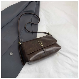 Detailed close-up of dark brown vintage crossbody bag with metal buckle on white background