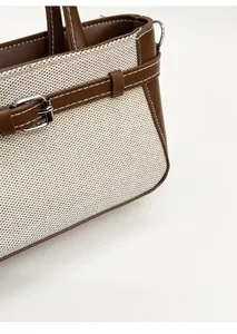 Detail of brown leather and beige woven fabric stitching with fine white contrast seams