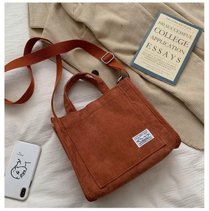 Detail of red-brown corduroy tote bag featuring vertical ribs and woven label accent