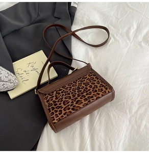 Detail of vintage leopard print crossbody bag on bedsheets and grey blazer