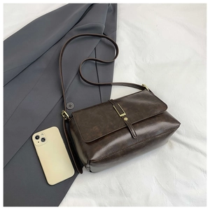 Detail view of a vintage dark brown leather tote bag with gold buckle and slim shoulder strap