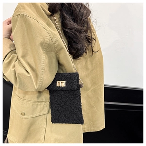 Detail of plush black crossbody bag featuring soft texture and gold chain strap