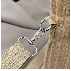 Macro view of khaki corduroy fabric with silver metal lobster clasp and woven strap detail