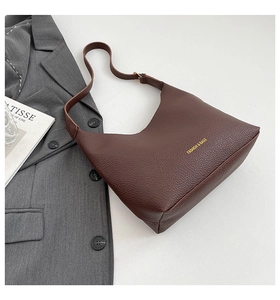 Detail of dark brown lychee leather texture and golden lettering on a fashion tote bag