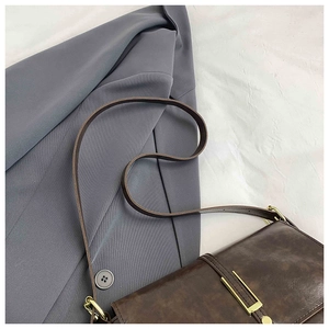 Detail of dark brown leather crossbody bag with vintage texture and gold buckle