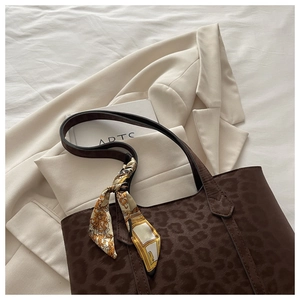 Détail d'un sac cabas en cuir marron foncé gaufré léopard avec un foulard en soie chic