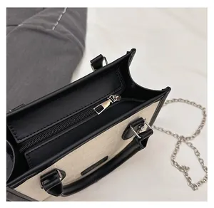 Detail of silver zipper closure and checkered embossing on black and white tote bag