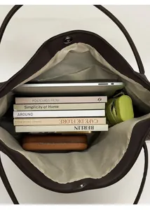 Vista dall'alto dell'interno della grande borsa tote marrone con laptop, libri e ombrello