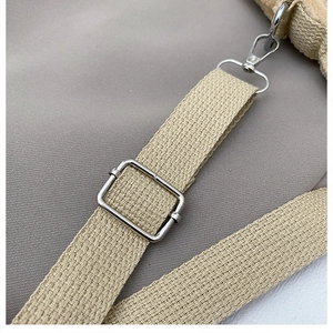 Close-up of adjustable canvas shoulder strap with silver metal buckle on a mini handbag