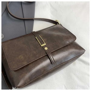 Detail of vintage dark brown tote bag with leather texture and gold metallic buckle