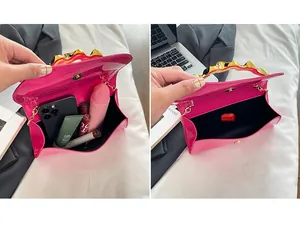 Detail view of pink patent leather clutch interior showing capacity for makeup and phone