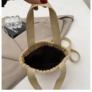 Detail view of mini plush handbag showing brown fabric lining and silver magnetic snap