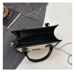 Top view of two-tone tote bag with interior zipper compartment and metal chain strap