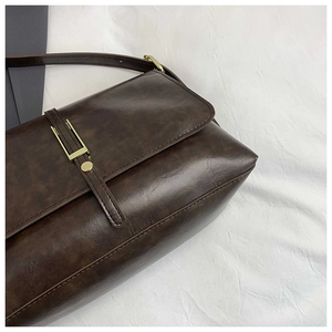 Close-up of vintage brown leather tote bag with elegant gold metal buckle and neat stitching