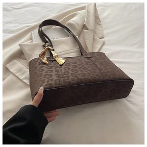 Détail d'un sac cabas marron à imprimé léopard avec foulard imprimé et longues anses