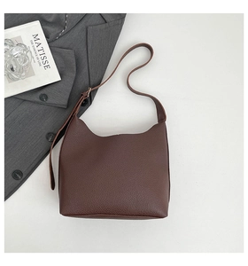Close-up of deep brown lychee grain leather tote bag with smooth shoulder straps