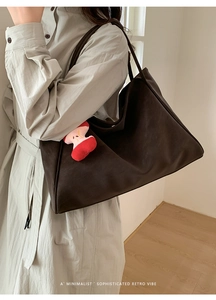 Dettaglio borsa tote marrone opaco con ciondolo a forma di mela in peluche e tracolla lunga