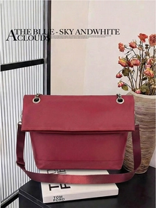 Detail of burgundy shoulder bag with silver eyelets and chain strap on decorative books