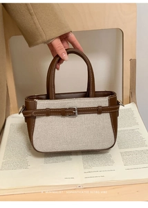 Close-up of retro woven handbag with brown leather straps and metal buckle detail