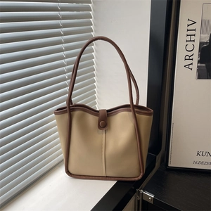 Sac fourre-tout beige minimaliste avec bordure marron sous une lumière de fenêtre douce