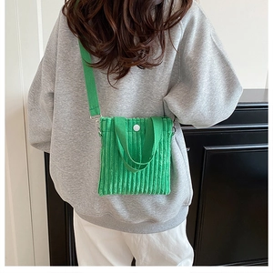 Vertical green corduroy mini crossbody bag shown on a model with white round button detail